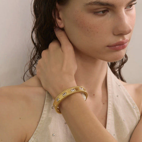 Woman wearing a gold bracelet with a neutral background Woman wearing a gold bracelet with a neutral background