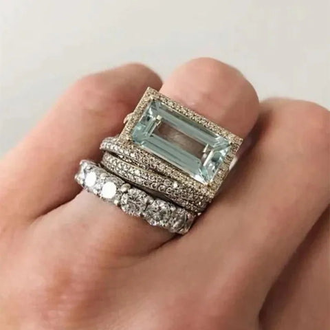 Two rings with gemstones on a hand against a neutral background Two rings with gemstones on a hand against a neutral background