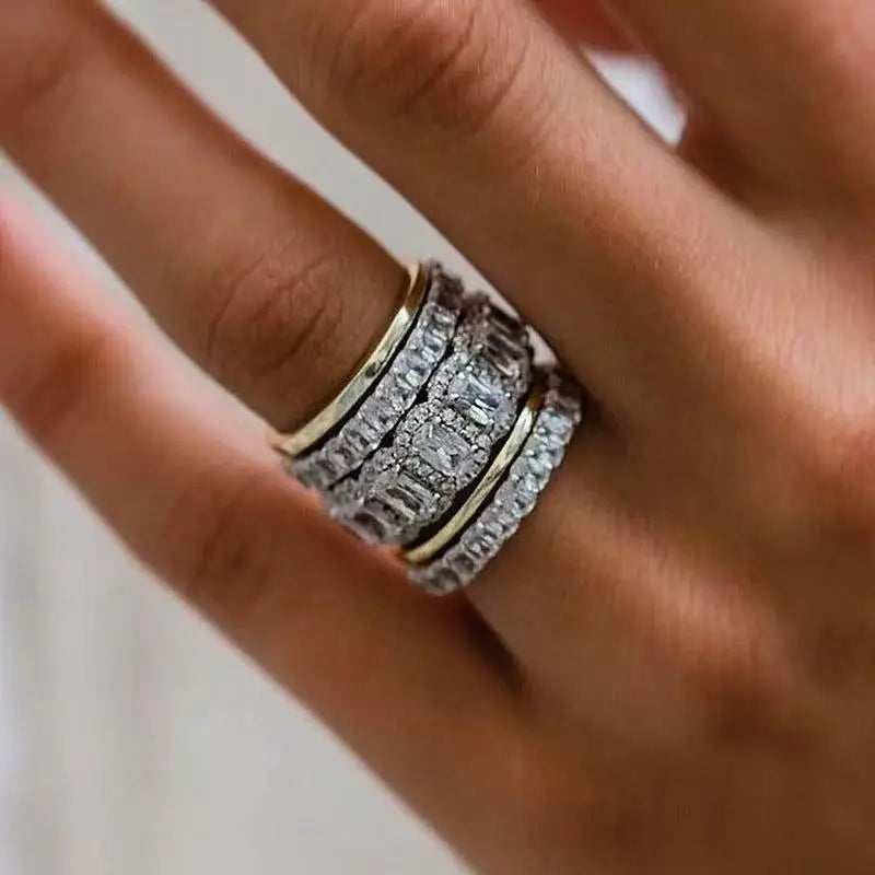 Close-up of a hand wearing multiple diamond rings on a neutral background