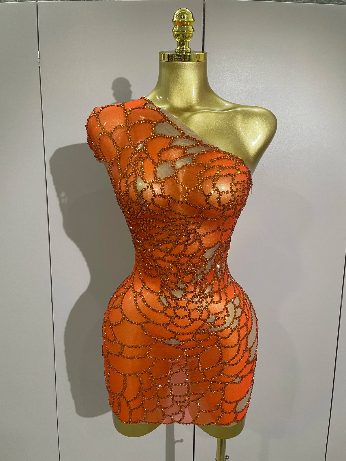 Orange beaded dress on a mannequin against a plain background